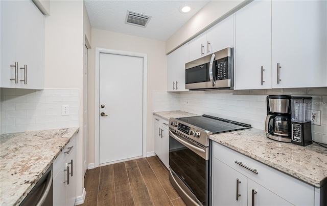 kitchen featuring appliances with stainless steel finishes, light stone counters, a textured ceiling, white cabinets, and dark hardwood / wood-style floors