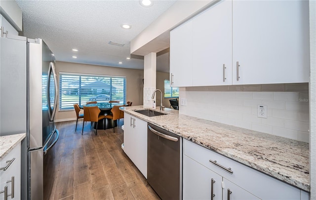 kitchen featuring sink, light stone countertops, appliances with stainless steel finishes, tasteful backsplash, and white cabinetry