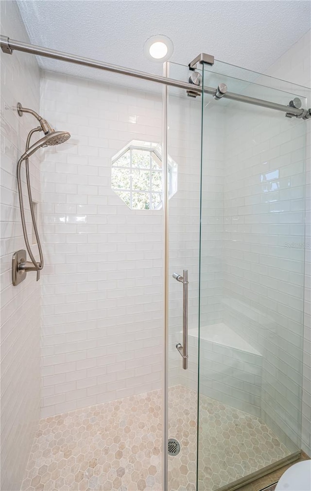 bathroom featuring a shower with door and a textured ceiling