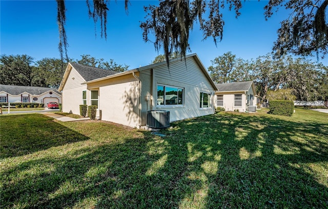 rear view of property featuring cooling unit and a lawn