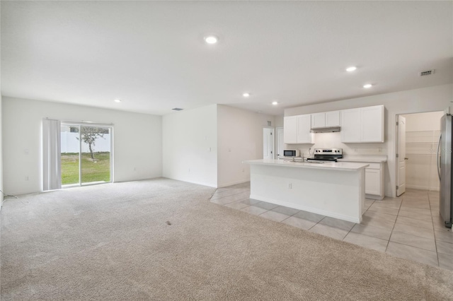 kitchen featuring light colored carpet, white cabinets, a center island with sink, and stainless steel appliances