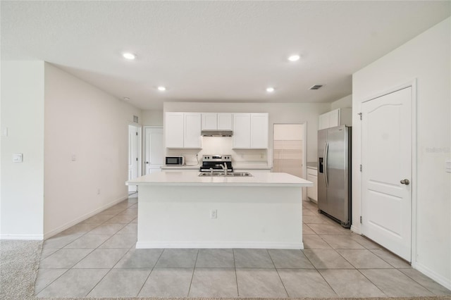 kitchen with white cabinetry, light tile patterned floors, stainless steel appliances, and a kitchen island with sink