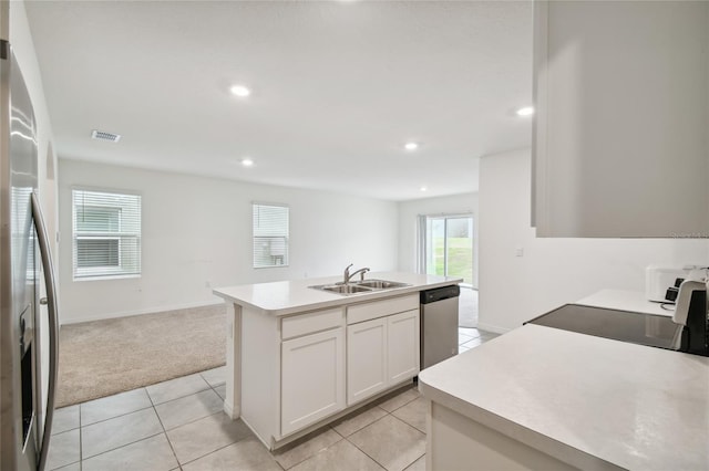 kitchen featuring white cabinets, stainless steel appliances, light carpet, an island with sink, and sink