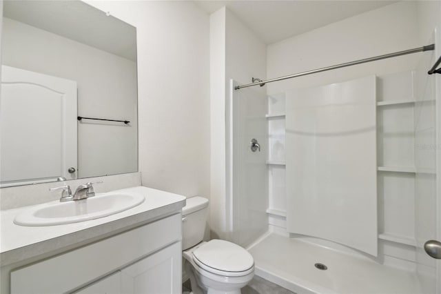 bathroom featuring toilet, a shower, and vanity