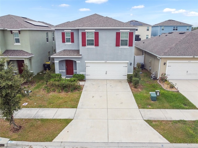 view of front of property with a garage, central AC, and a front yard