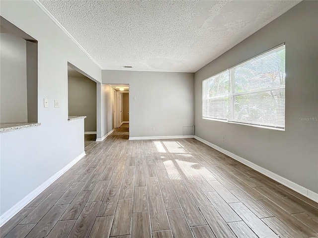 empty room with a textured ceiling and light wood-type flooring