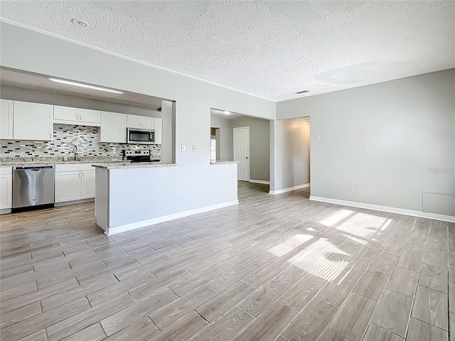 kitchen with a textured ceiling, light hardwood / wood-style floors, white cabinetry, and stainless steel appliances