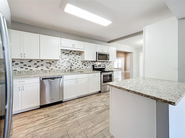 kitchen with white cabinetry, sink, light hardwood / wood-style floors, and appliances with stainless steel finishes