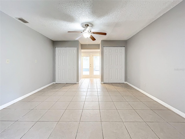 unfurnished bedroom featuring ceiling fan, light tile patterned floors, a textured ceiling, and french doors