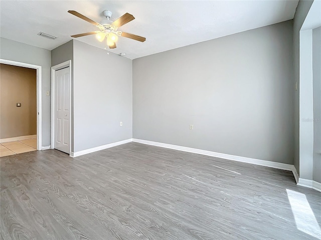 unfurnished bedroom featuring a closet, light hardwood / wood-style floors, and ceiling fan