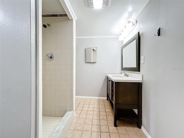 bathroom with tile patterned floors, vanity, a tile shower, and crown molding