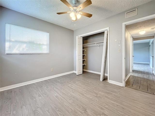 unfurnished bedroom featuring ceiling fan, light hardwood / wood-style floors, and a textured ceiling