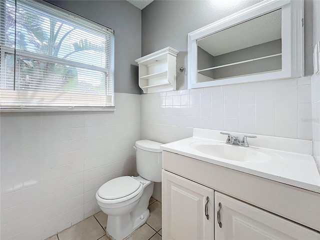 bathroom featuring tile patterned flooring, vanity, toilet, and tile walls