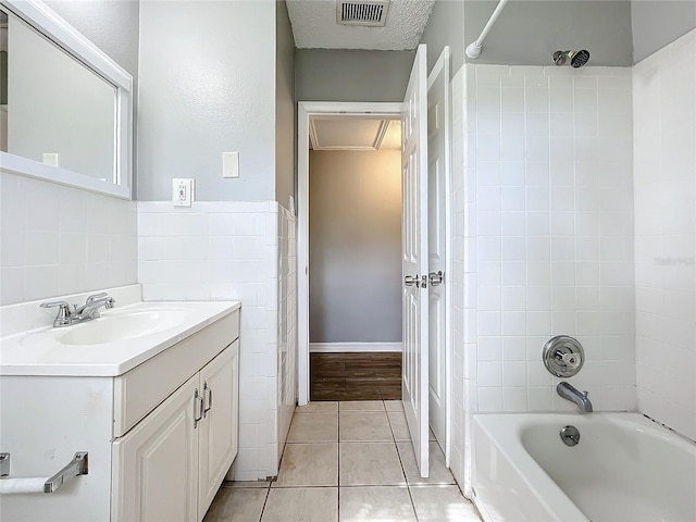 bathroom featuring tile patterned floors, vanity, a textured ceiling, and tiled shower / bath