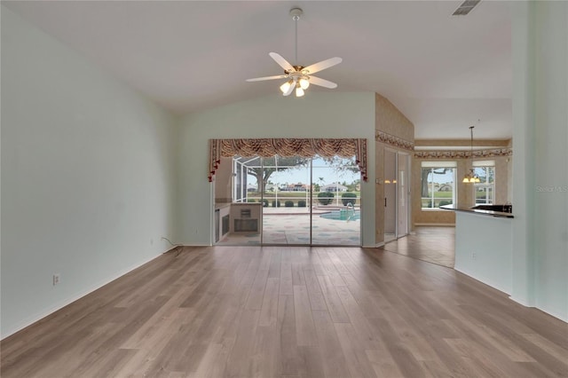 unfurnished living room with lofted ceiling, hardwood / wood-style floors, and ceiling fan with notable chandelier