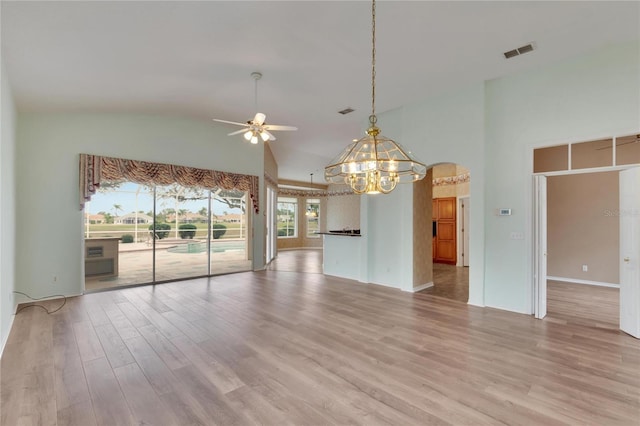 spare room featuring ceiling fan with notable chandelier, light wood-type flooring, and high vaulted ceiling