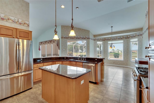 kitchen with decorative light fixtures, sink, stainless steel appliances, and vaulted ceiling