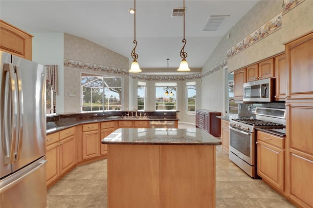 kitchen with sink, a center island, pendant lighting, vaulted ceiling, and appliances with stainless steel finishes