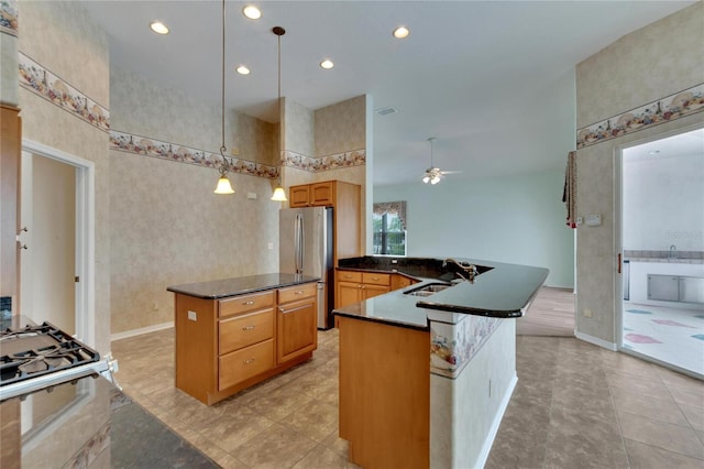 kitchen featuring ceiling fan, sink, kitchen peninsula, decorative light fixtures, and appliances with stainless steel finishes