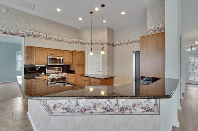 kitchen with pendant lighting, dark stone counters, a spacious island, sink, and stainless steel appliances