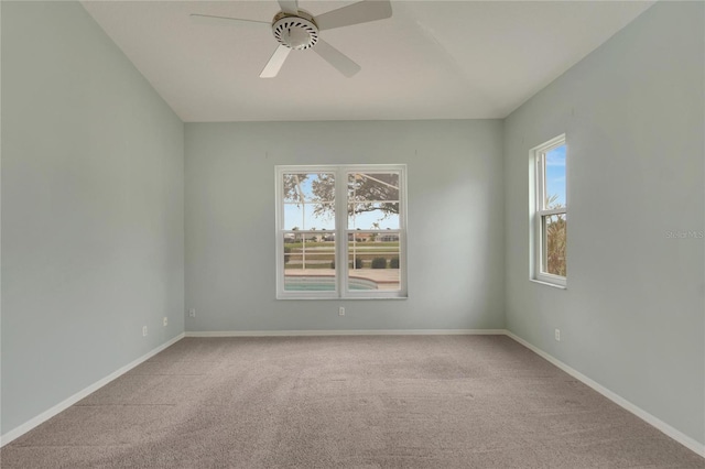 carpeted spare room featuring a wealth of natural light and ceiling fan