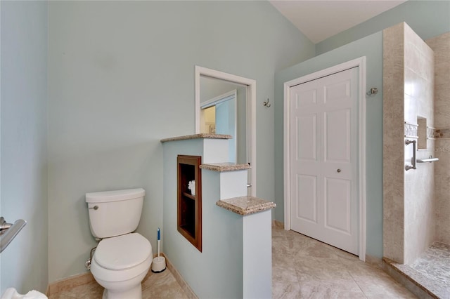 bathroom featuring a tile shower, toilet, and tile patterned floors