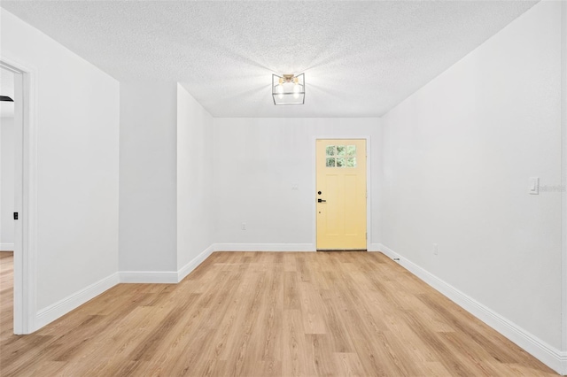 empty room featuring a textured ceiling and light hardwood / wood-style flooring