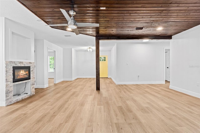 basement with ceiling fan, wood ceiling, a fireplace, and light hardwood / wood-style flooring