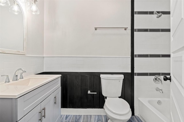 full bathroom featuring vanity, tiled shower / bath combo, and toilet