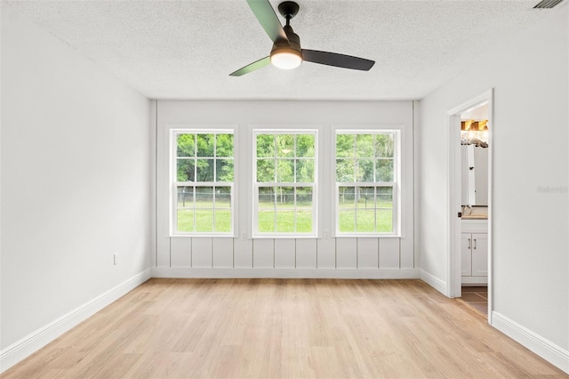 spare room featuring a textured ceiling, light wood-type flooring, and a wealth of natural light