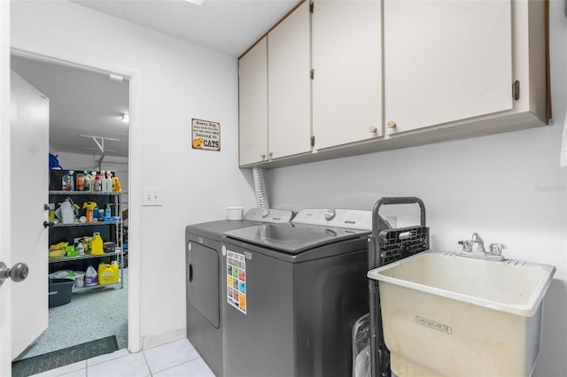 laundry area with cabinets, light tile patterned floors, sink, and washing machine and clothes dryer