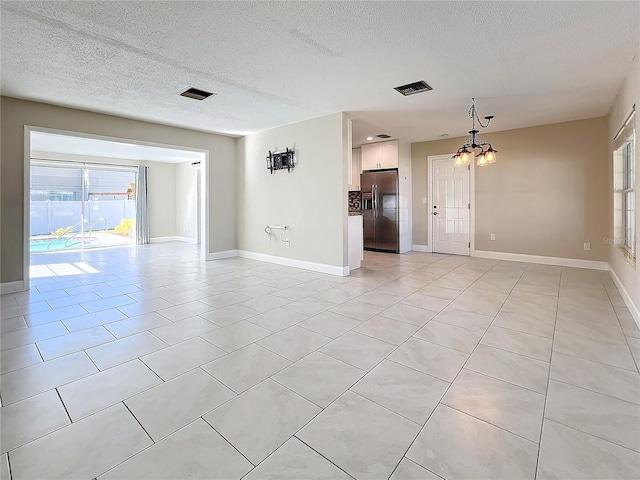 spare room featuring light tile patterned floors, a textured ceiling, and an inviting chandelier