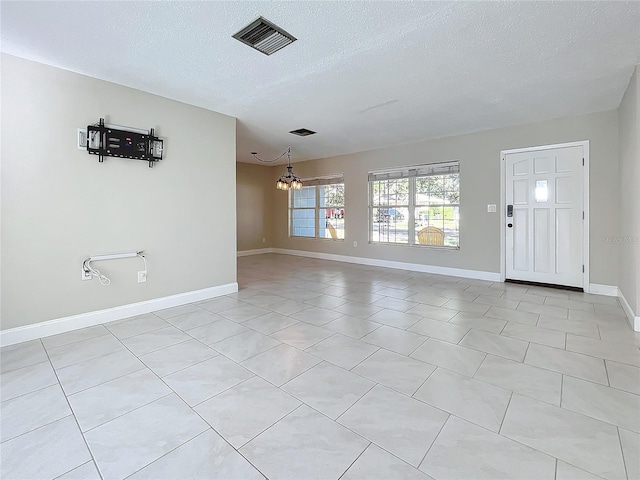 tiled foyer with a notable chandelier and a textured ceiling