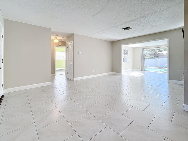 tiled empty room with a textured ceiling