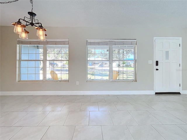 interior space with a notable chandelier, light tile patterned floors, and a textured ceiling