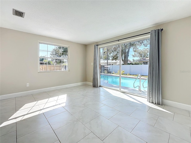 unfurnished room with light tile patterned floors and a textured ceiling