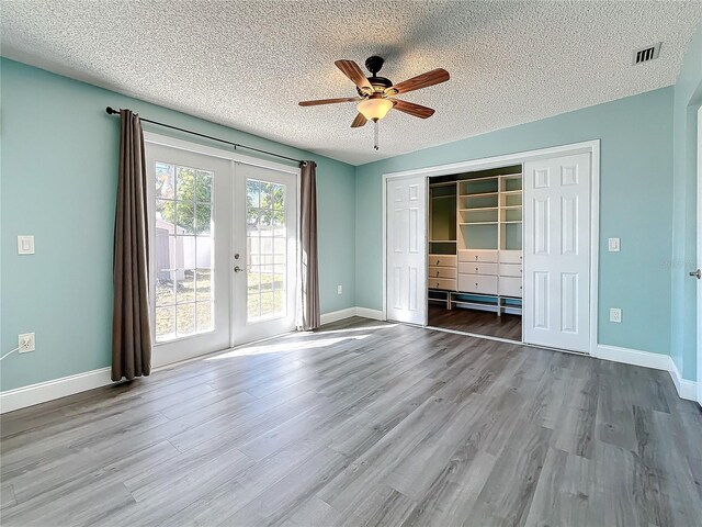 unfurnished living room with french doors, a textured ceiling, and hardwood / wood-style flooring