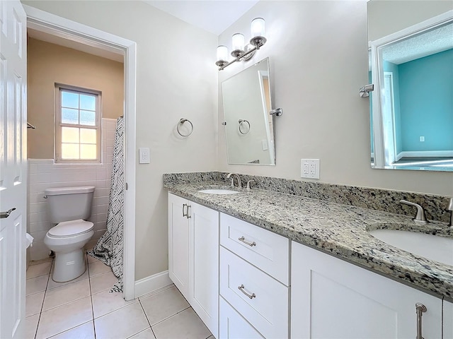 bathroom with toilet, vanity, tile patterned floors, and tile walls