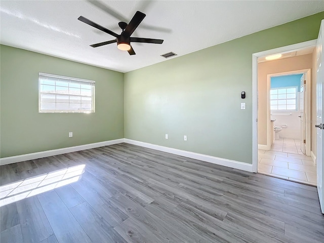 spare room with a textured ceiling, hardwood / wood-style flooring, plenty of natural light, and ceiling fan