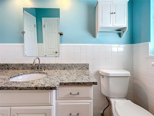 bathroom featuring vanity, tile walls, and toilet