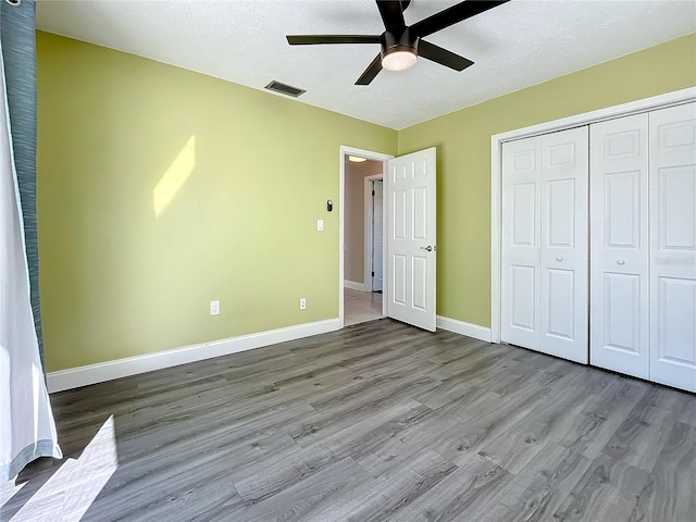 unfurnished bedroom featuring ceiling fan, a closet, a textured ceiling, and light hardwood / wood-style flooring