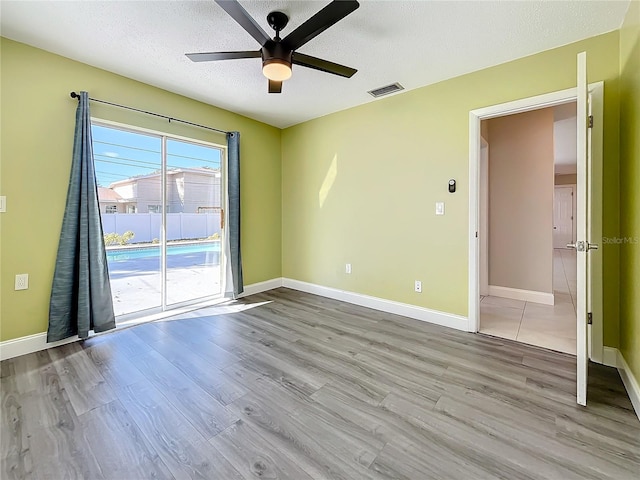 empty room featuring a textured ceiling, light hardwood / wood-style floors, and ceiling fan