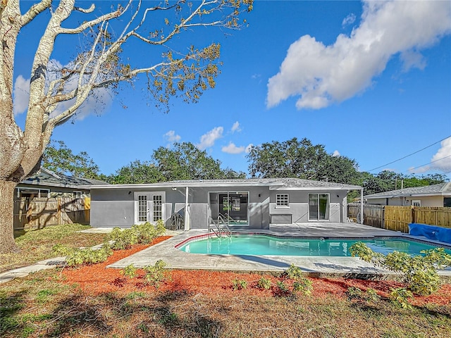 rear view of property with a fenced in pool, a patio area, and french doors