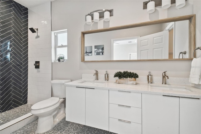 bathroom with toilet, tile patterned flooring, vanity, and tiled shower