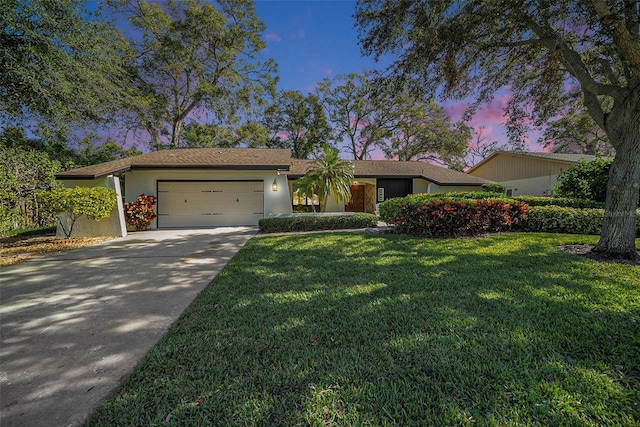 ranch-style home featuring a lawn and a garage