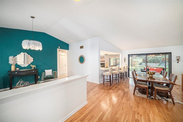 dining room featuring wood-type flooring, an inviting chandelier, and vaulted ceiling