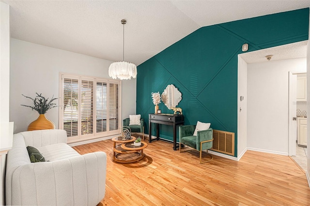 sitting room with light hardwood / wood-style floors, vaulted ceiling, and a notable chandelier