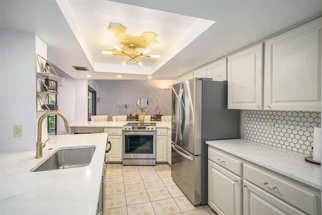 kitchen featuring stainless steel appliances, a raised ceiling, sink, light tile patterned floors, and white cabinets