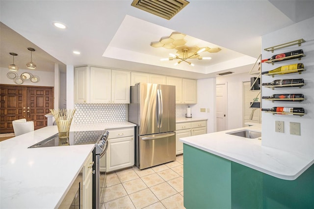 kitchen featuring white cabinets, decorative backsplash, a raised ceiling, and stainless steel appliances