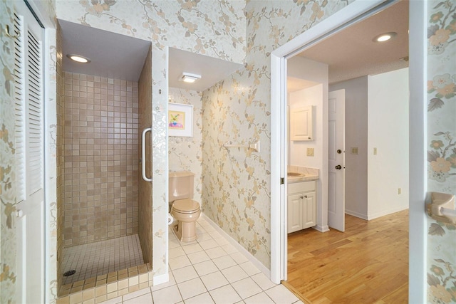 bathroom with toilet, vanity, tiled shower, and tile patterned floors